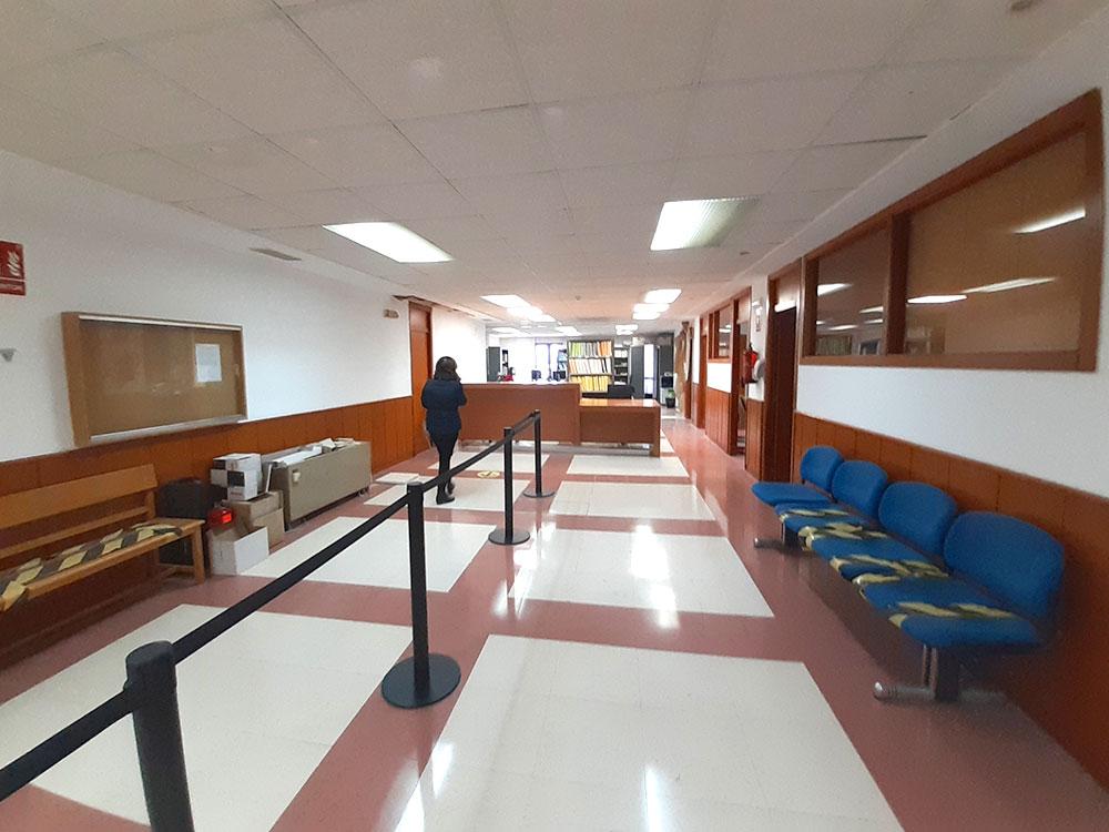 Pasillo de oficinas con accesos a despachos y mostrador al fondo