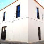 Exterior del edificio, con paredes blancas y ventanas verticales en planta baja y piso superior